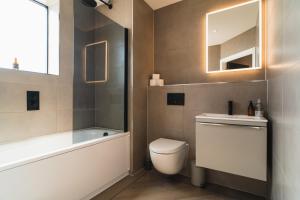 a bathroom with a toilet and a tub and a sink at Penthouse - Harbour Views in Poole