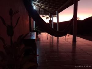a hammock on a porch with the sunset in the background at Sítio Ramos casa azul in Cunha