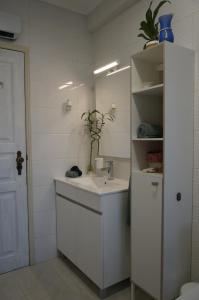 a white bathroom with a sink and a mirror at Beach Front Apartment in Gafanha da Nazaré