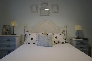 um quarto com uma cama branca com almofadas e 2 candeeiros em Beach Front Apartment em Gafanha da Nazaré