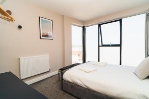 a bedroom with a bed and large windows at Penthouse - Harbour Views in Poole