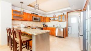 a kitchen with wooden cabinets and a island with chairs at Encanto Living 1104 by Kivoya in Puerto Peñasco