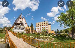 a wooden walkway leading to a large building with a pond at Teslić Apartman NiA in Teslić