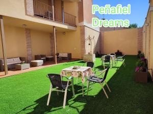 un patio con mesa y sillas en el césped en PEÑAFIEL DREAMS CON JACUZZI 4 PERSONAS en Peñafiel