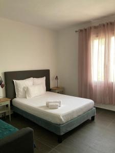 a bedroom with a bed with white sheets and a window at Soleil Corse in Saint-Florent