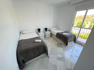 2 łóżka w białym pokoju z oknem w obiekcie Luxury three bedroom apartment at Estepona w mieście Estepona +36 zdjęć