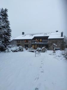 un edificio cubierto de nieve con huellas en la nieve en B&B Emmylou en Gouvy