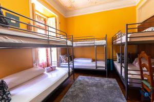 リスボンにあるLisbon Angels Hostelの黄色の壁の客室で、二段ベッド3組が備わります。