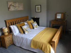 um quarto com uma cama grande e almofadas amarelas em Shepherds Cottage em Shrewsbury