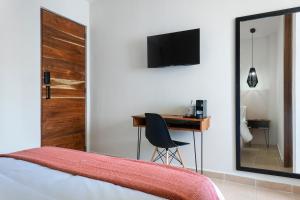 a bedroom with a desk and a bed and a mirror at Rodina - Hotel Boutique in Playa del Carmen