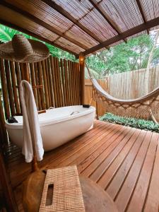 a bath tub on a wooden deck with a hammock at HaraMatha in Barra Grande