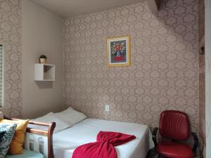 um quarto com uma cama e uma cadeira vermelha em Condomínio DINASEG em Rio Branco
