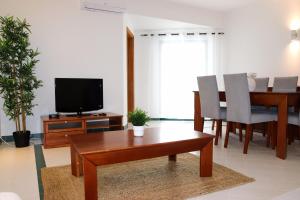 ein Wohnzimmer mit einem Holztisch und einem TV in der Unterkunft Apartamento Salgados Mar in Albufeira