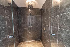 a bathroom with a shower with black tiles at Best Western Plus Hotel Ilulissat in Ilulissat