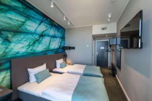 two beds in a room with a painting on the wall at Best Western Plus Hotel Ilulissat in Ilulissat