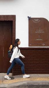 una mujer caminando por una acera delante de un cartel en Casa Manoa en Sesquilé