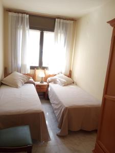 2 camas en una habitación con ventana en APARTAMENTS CASA NANDO., en Esterri d'Àneu