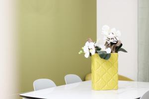 un vaso giallo con fiori bianchi su un tavolo di Altum Villare Apartments a Ravenna