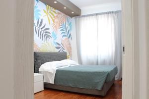 1 dormitorio con cama y papel pintado tropical en Altum Villare Apartments, en Rávena