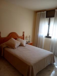 a bedroom with a bed with white sheets and a window at APARTAMENTS CASA NANDO. in Esterri d'Àneu