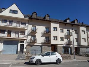 un coche blanco estacionado frente a un edificio en APARTAMENTS CASA NANDO., en Esterri d'Àneu