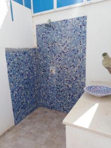 La salle de bains est pourvue d'une douche et d'un mur en carrelage bleu. dans l'établissement Maison typiques (houche) avec piscine, à Houmt Souk