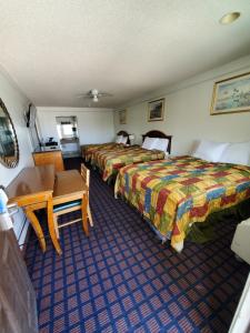 a hotel room with two beds and a desk at Deluxe Inn and Suites in Raymondville +107 photos