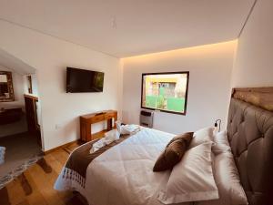 a bedroom with a bed and a flat screen tv at Sonho Real Suítes in Lavras Novas