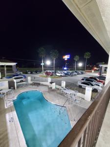 a swimming pool at night with a parking lot at Deluxe Inn and Suites in Raymondville
