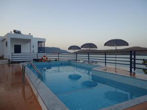 ein großer Pool mit Sonnenschirmen auf einem Gebäude in der Unterkunft Kavos Bay Apartments Elounda in Elounda