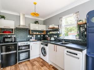 uma cozinha com armários brancos e uma máquina de lavar e secar roupa em Kilmartin View em Lochgilphead