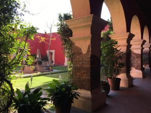 une cour avec un bâtiment rouge et des plantes dans l'établissement Quinta Luna, à Cholula