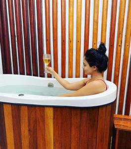 Eine Frau, die ein Glas Wein in einer Badewanne hält. in der Unterkunft Meditarranee Residence in Camocim