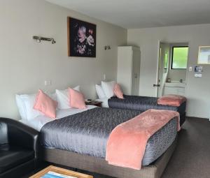 um quarto de hotel com duas camas e um sofá em Arran Motel em Te Anau