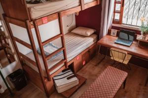 a room with bunk beds and a desk with a laptop at Garoa Hostel Party Bar in São Paulo