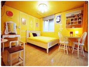 Dormitorio amarillo con cama, mesa y sillas en Han River Residence & Guesthouse, en Seúl