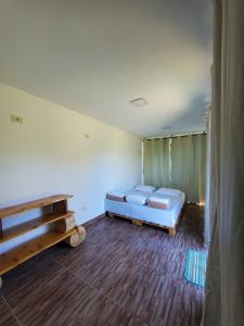 a room with a bed and a wooden floor at IVOS Hostel & Camping in Itanhandu