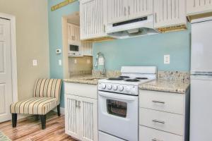 a kitchen with white cabinets and a stove and a chair at Bungalow Beach Place 6 in Clearwater Beach +17 photos