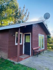 a small red building with a bench in front of it at Cabañas borde rio in Villarrica