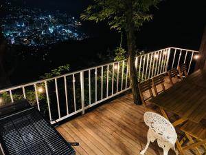 a wooden deck with a table and chairs on it at night at 熱海天海ヴィラ/ Atami Tenkai Villa in Atami