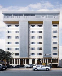 een groot wit gebouw met auto's geparkeerd op een parkeerplaats bij Hotel Carmel in Lima