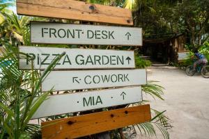 a sign with several street signs on a pole at Selina Tulum in Tulum