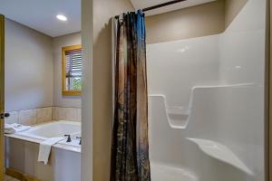 y baño con bañera, lavamanos y ducha. en Bear Cove Falls #4133 en Pigeon Forge