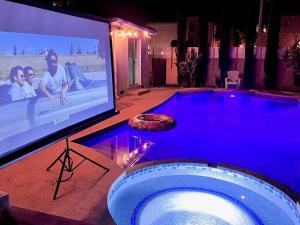 a swimming pool with a tv and a large screen at Endless summer in LA *HEATED POOL/HOT TUB/CABANA* in Los Angeles