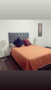 a bedroom with a bed with an orange bedspread and two lamps at STUDIO RECIEN RENOVADO EN EL CENTRO DE LA CIUDAD DE MORELIA. in Morelia +2 photos