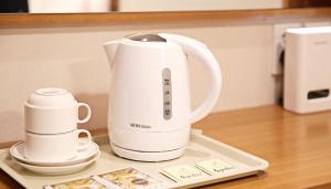 a white electric kettle sitting on a counter with two cups at Hotel Skypark Dongdaemun I in Seoul