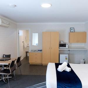 a room with a bed and a desk and a kitchen at The Busselton Motel in Busselton
