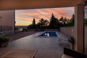 un patio trasero con piscina y puesta de sol en Apartments Villa Antonia, en Jadranovo