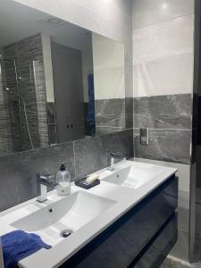 La salle de bains est pourvue de 2 lavabos et d'un grand miroir. dans l'établissement Spacious Ground Floor Luxury Apartment with underground parking, à Castillo de Sabinillas