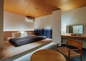 a bedroom with a bed and a tv and a chair at Hotel Graphy Nezu in Tokyo